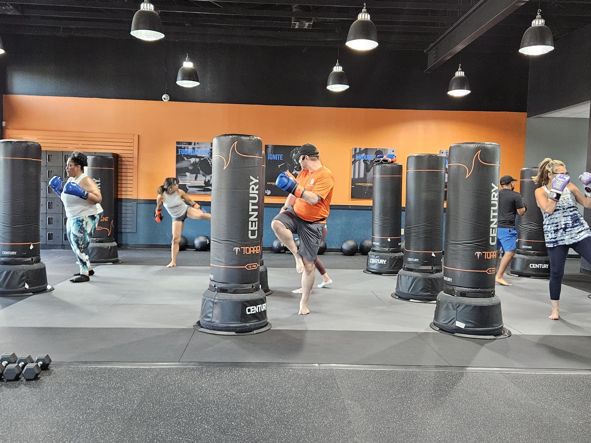 A coach-led kickboxing class mid-round at Vibes Lifestyle in Bedford, TX, with members throwing kicks and punches on the bags